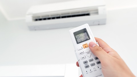 hand wijst met afstandsbediening naar de airconditioner